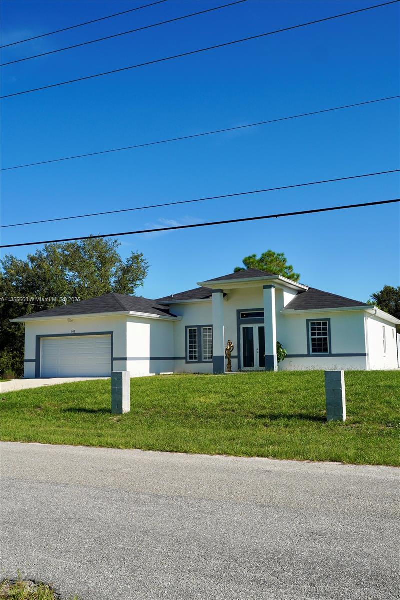 A single-story house with a white exterior, gray trim, and a two-car garage — 105 E 15th st, Lehigh Acres FL 33972, LEHIGH ACRES, FL