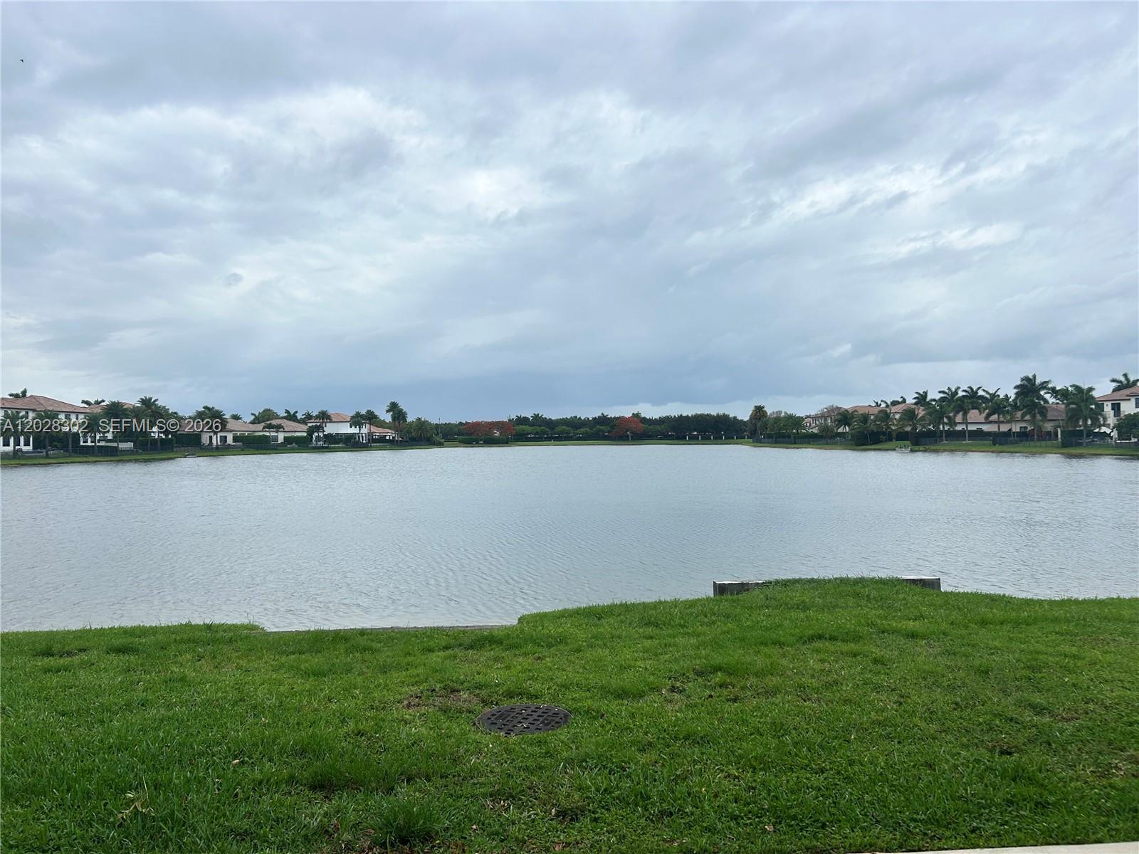 A grassy lawn overlooks a large lake surrounded by residential houses under a blue sky — 3057 Tortola Way, Hollywood FL 33024, HOLLYWOOD, FL