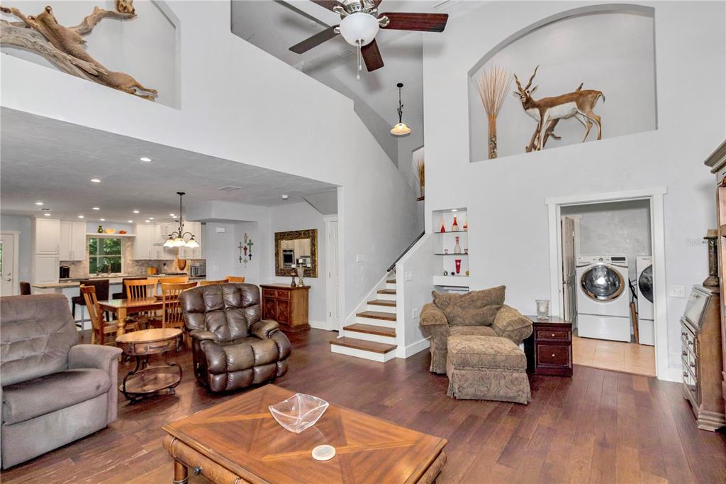 A living room with wood floors, a staircase, and a view into the kitchen — 26354 NW 94TH AVENUE, HIGH SPRINGS, FL