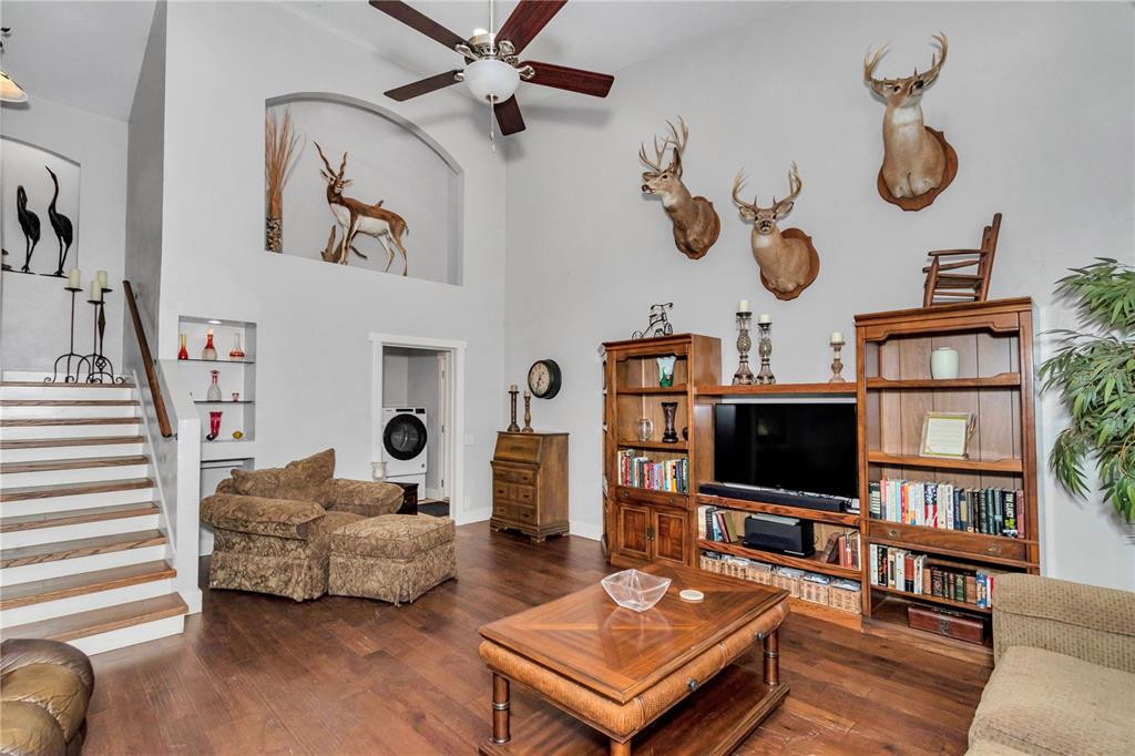 A living room features wood floors, a staircase, built-in shelving, and several animal taxidermy mounts — 26354 NW 94TH AVENUE, HIGH SPRINGS, FL