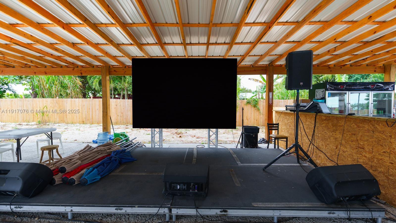 An outdoor covered stage features a large black screen, audio equipment, and a wooden bar area — 16860 SW 177TH AVE, Miami FL 33187, MIAMI, FL