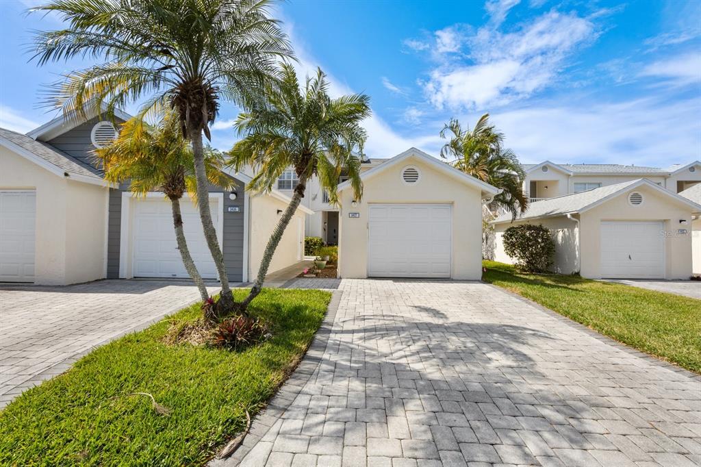 A view of three garage doors and paved driveways in front of residential buildings with palms — 11600 SHIPWATCH DRIVE UNIT 1417, LARGO, FL