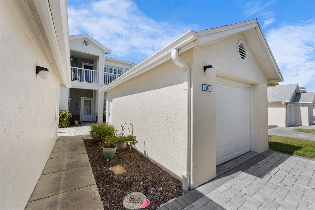 A view of a garage exterior with a paved driveway and a small garden bed — 11600 SHIPWATCH DRIVE UNIT 1417, LARGO, FL