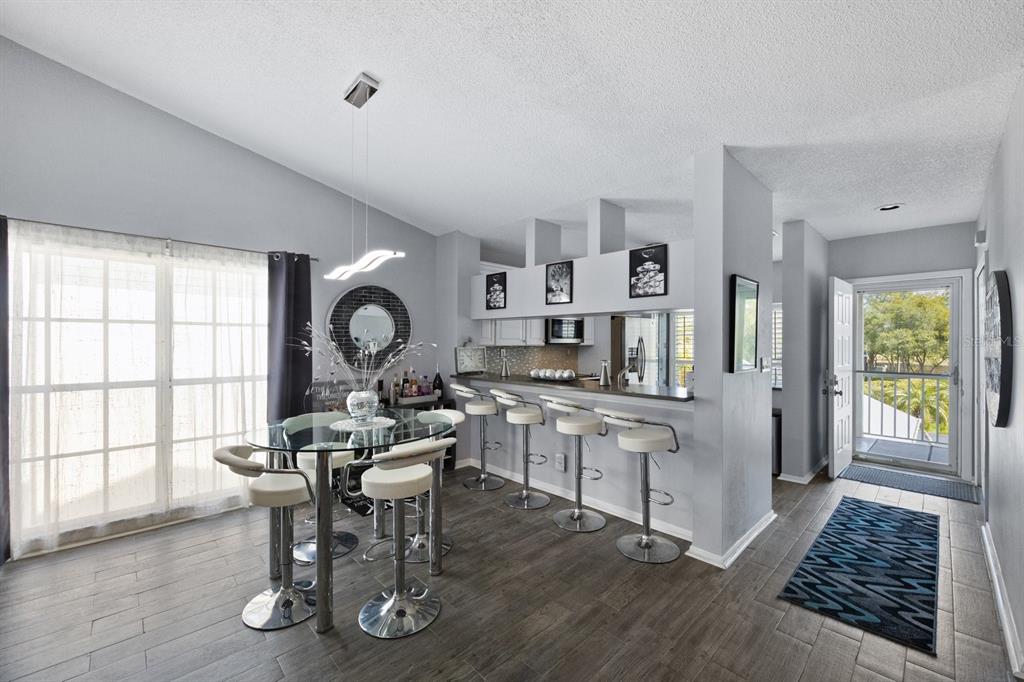 A dining area with a glass table and bar seating opens to an entryway and kitchen — 11600 SHIPWATCH DRIVE UNIT 1417, LARGO, FL