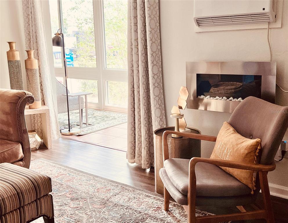 A living room features a fireplace, an armchair with a pillow, and a sliding door — 151 N ORLANDO AVENUE UNIT 203, WINTER PARK, FL