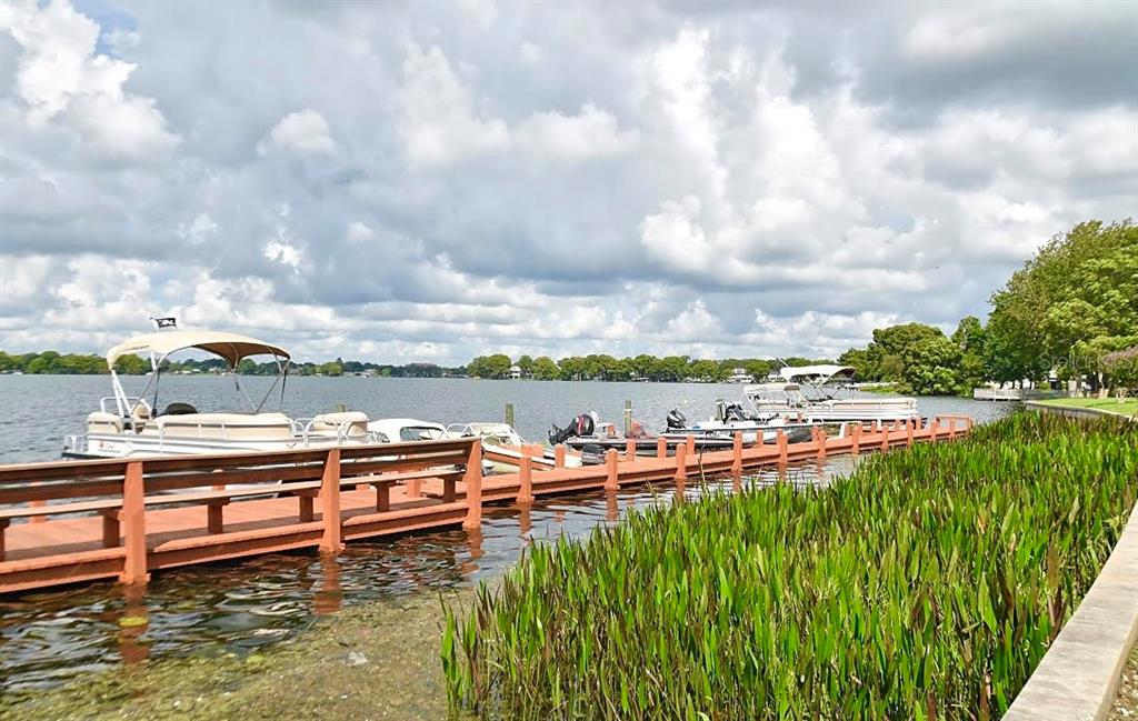 A wooden dock extends into a lake with several pontoon boats moored alongside it — 151 N ORLANDO AVENUE UNIT 203, WINTER PARK, FL