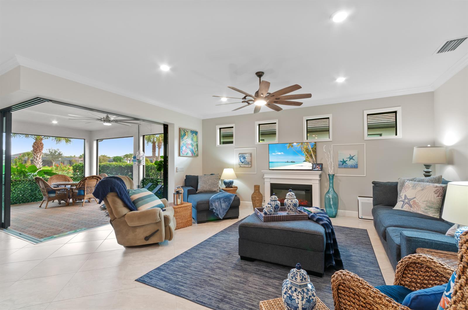 A living room features a fireplace, blue furniture, a large rug, and sliding glass doors — 5947 Prosperity Lane, Ave Maria FL 34142, AVE MARIA, FL