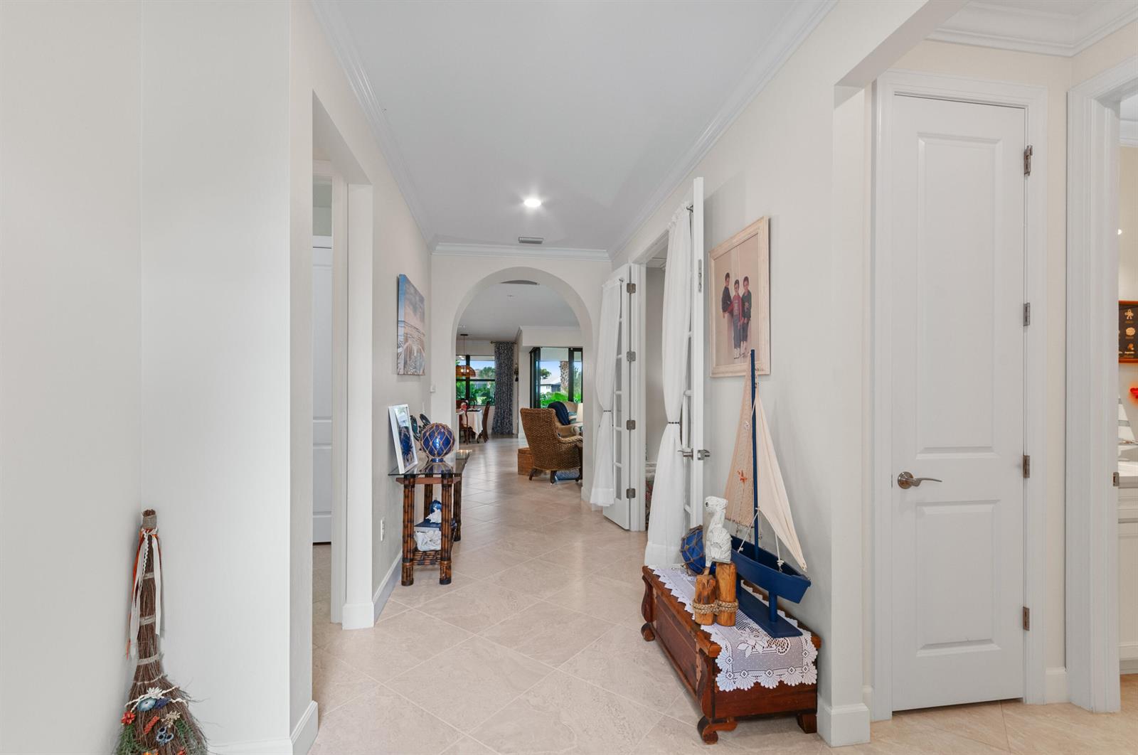 A bright hallway with tile floors leads through an arched doorway toward a living area — 5947 Prosperity Lane, Ave Maria FL 34142, AVE MARIA, FL