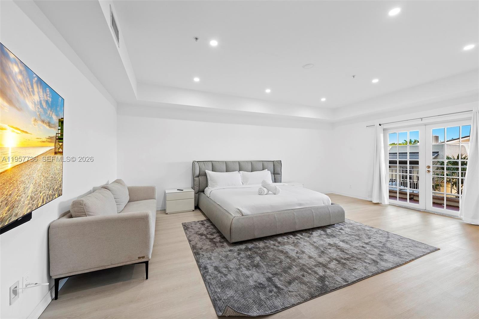 A bedroom features a gray upholstered bed, a matching sofa, and a balcony with glass doors — 1415 Sunset Harbour Dr # 204, Miami Beach FL 33139, MIAMI BEACH, FL