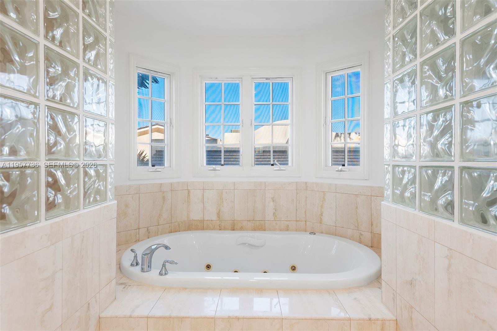 A white jetted bathtub is set into a tiled alcove flanked by glass block walls — 1415 Sunset Harbour Dr # 204, Miami Beach FL 33139, MIAMI BEACH, FL