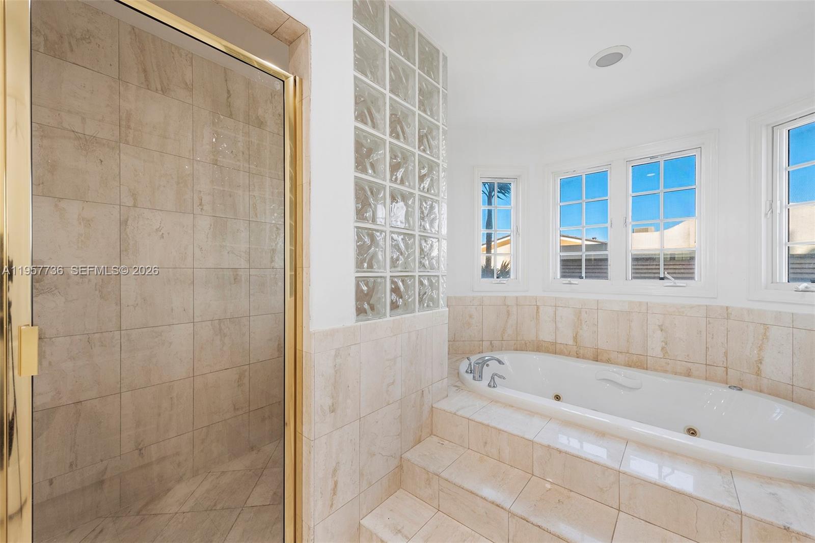 A bathroom features a tiled shower, a jetted tub, and a glass block wall — 1415 Sunset Harbour Dr # 204, Miami Beach FL 33139, MIAMI BEACH, FL