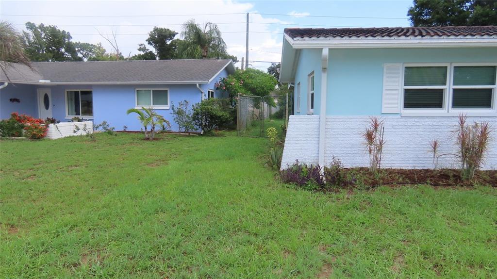 The exterior of two light blue houses with white trim and a grassy yard — 2459 RUTLAND LANE, CLEARWATER, FL