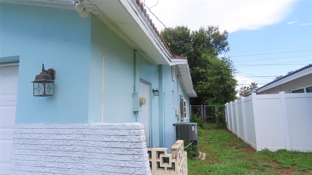 The exterior of a light blue house features a white brick base and side yard — 2459 RUTLAND LANE, CLEARWATER, FL
