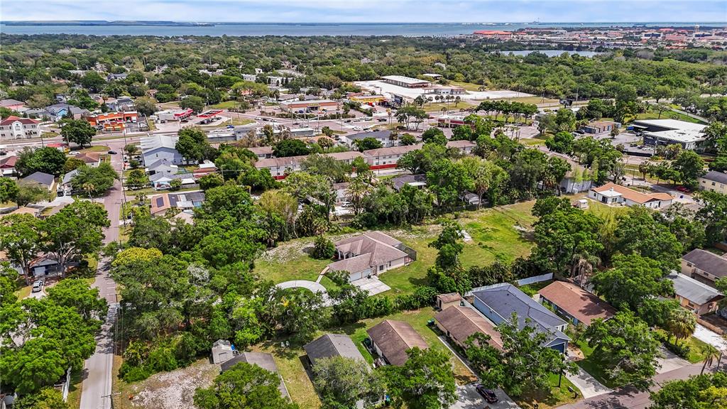 An aerial view shows a residential neighborhood with houses, trees, and a distant body of water — 3902 W ELROD AVENUE, TAMPA, FL