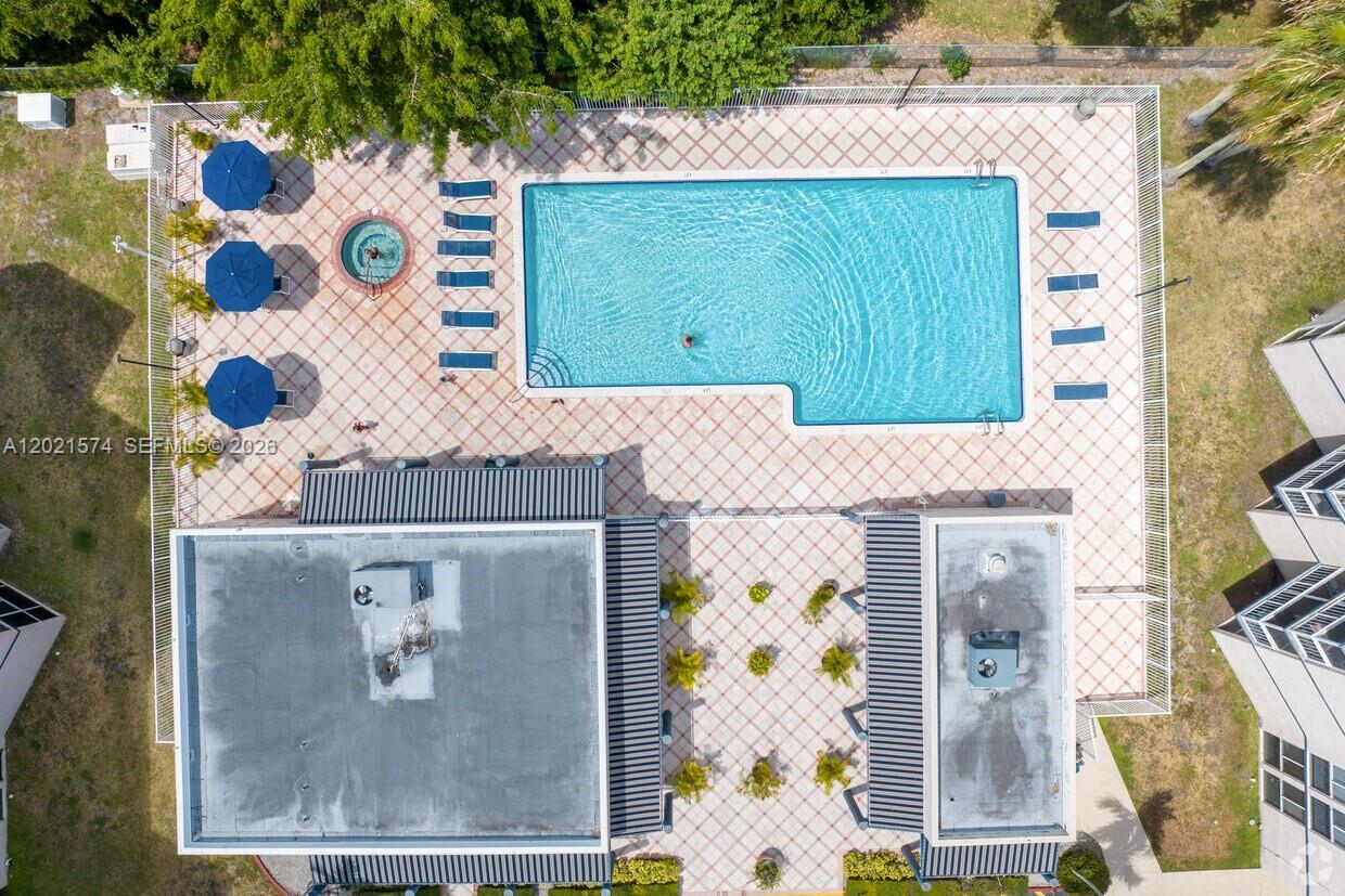 An aerial view shows a swimming pool, hot tub, lounge chairs, and two flat-roofed buildings — 7075 NW 186th St # C207, Hialeah FL 33015, HIALEAH, FL