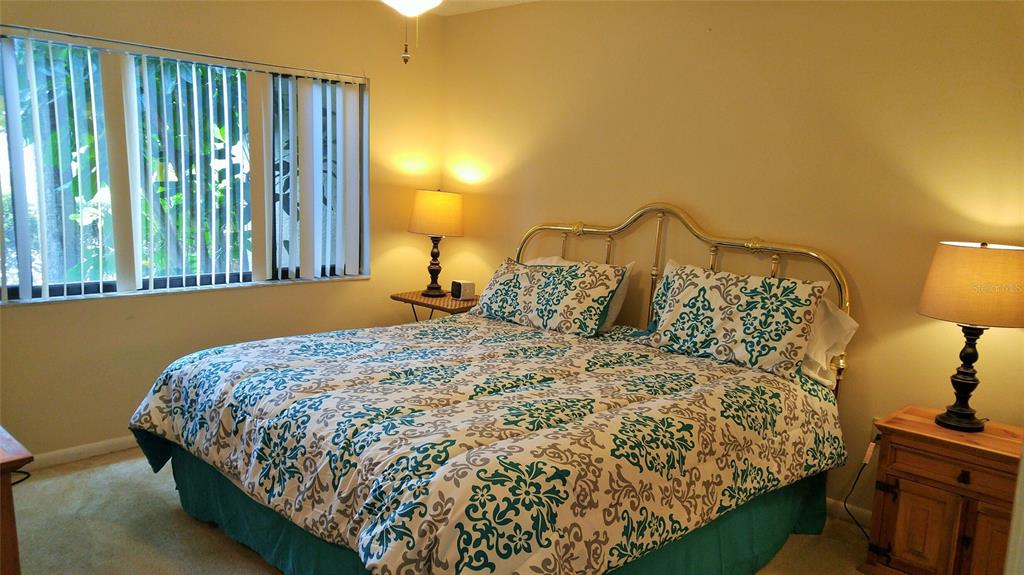 A bedroom features a bed with a patterned comforter, a brass headboard, and two lamps — 5677 ASHTON LAKE DRIVE UNIT 11, SARASOTA, FL