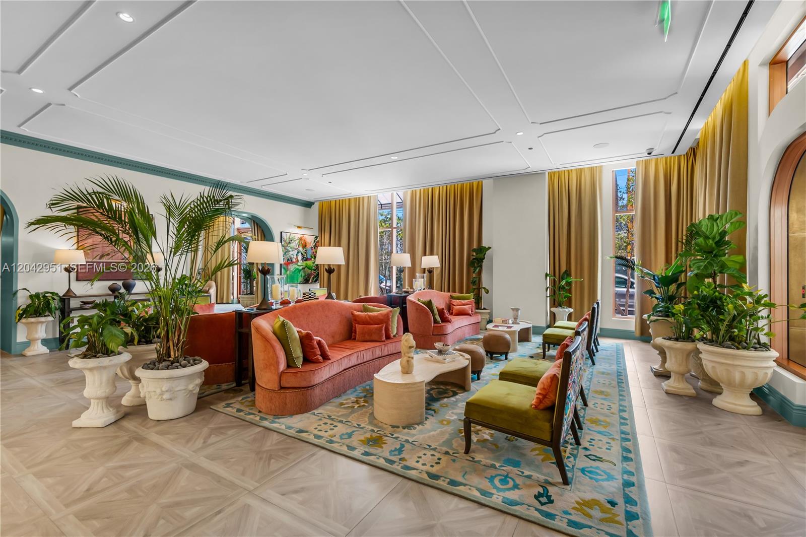 A spacious living room features coral sofas, green accent chairs, and large potted plants — 2700 NW 2nd Avenue # 337, Miami FL 33127, MIAMI, FL