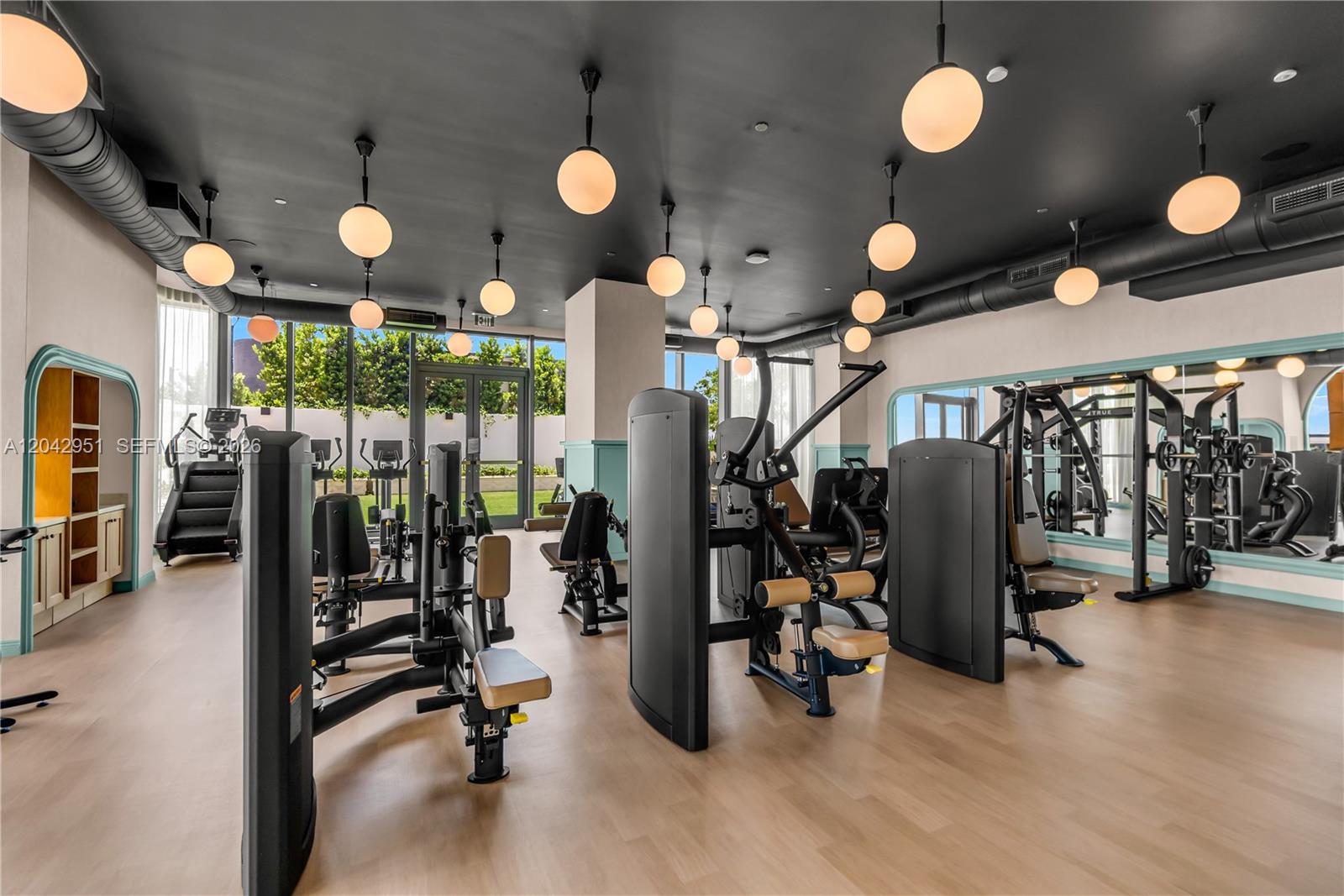 A modern gym features black ceilings, pendant globe lighting, exercise equipment, and light wood flooring — 2700 NW 2nd Avenue # 337, Miami FL 33127, MIAMI, FL