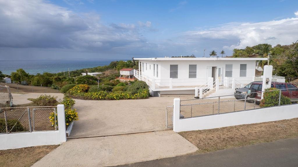 A white, single-story house with a flat roof sits on a hill overlooking the ocean — 759B COM. VILLA BORINQUEN, VIEQUES, PR