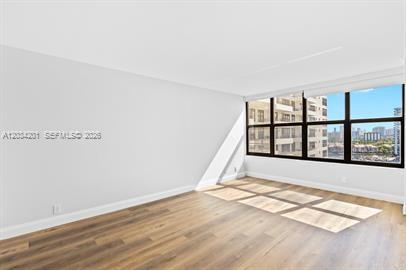 An empty room with light gray walls, wood-look flooring, and large windows overlooking a city — 2500 Parkview Dr # 1216, Hallandale Beach FL 33009, HALLANDALE BEACH, FL