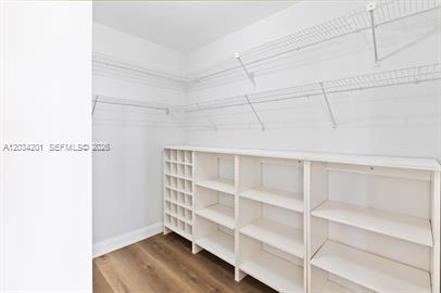 A walk-in closet features white wire shelving, built-in wooden storage units, and wood-look flooring — 2500 Parkview Dr # 1216, Hallandale Beach FL 33009, HALLANDALE BEACH, FL