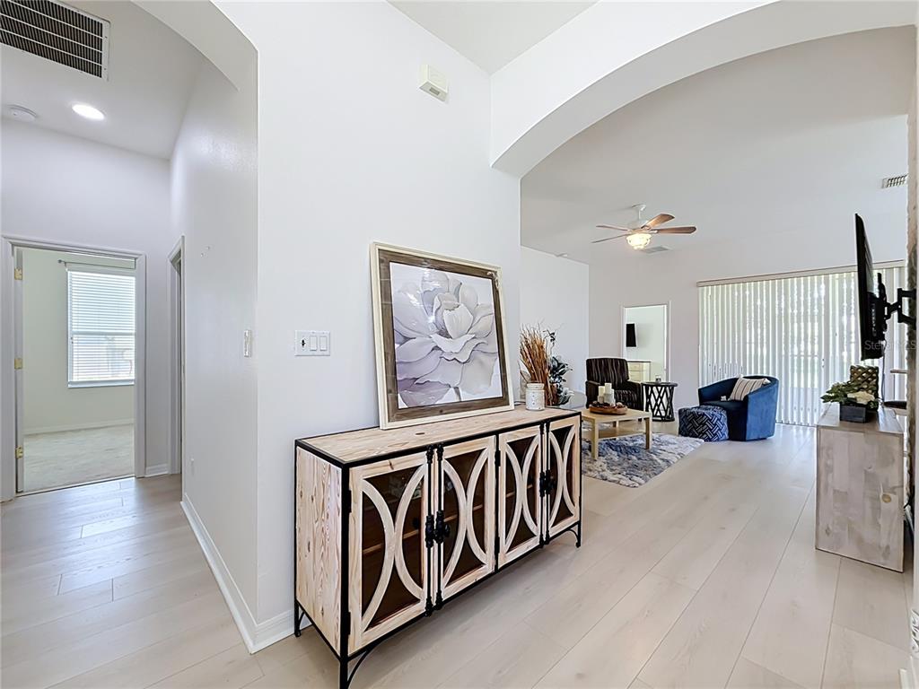 A light-floored entryway leads into a living room with a console table and wall art — 25206 ORMOND COURT, LEESBURG, FL