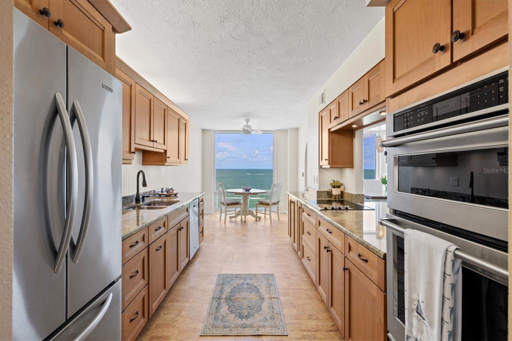 A galley kitchen with wood cabinets and stainless steel appliances overlooks the ocean — 2425 GULF OF MEXICO DRIVE UNIT 10F, LONGBOAT KEY, FL