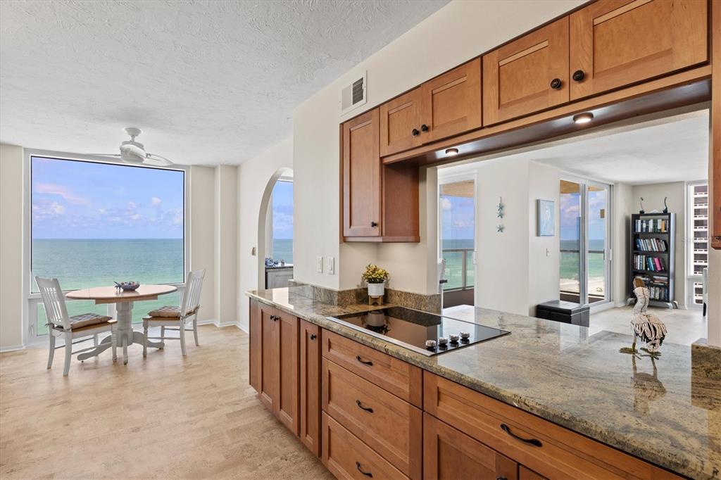 A kitchen with wood cabinets and granite countertops overlooks a dining area with ocean views — 2425 GULF OF MEXICO DRIVE UNIT 10F, LONGBOAT KEY, FL