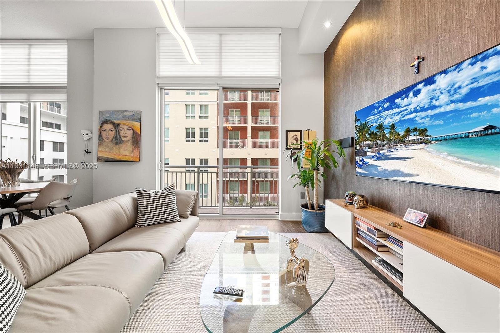 A modern living room features a beige sofa, glass coffee table, and wall-mounted television — 9066 SW 73rd Ct # 405, Miami FL 33156, MIAMI, FL