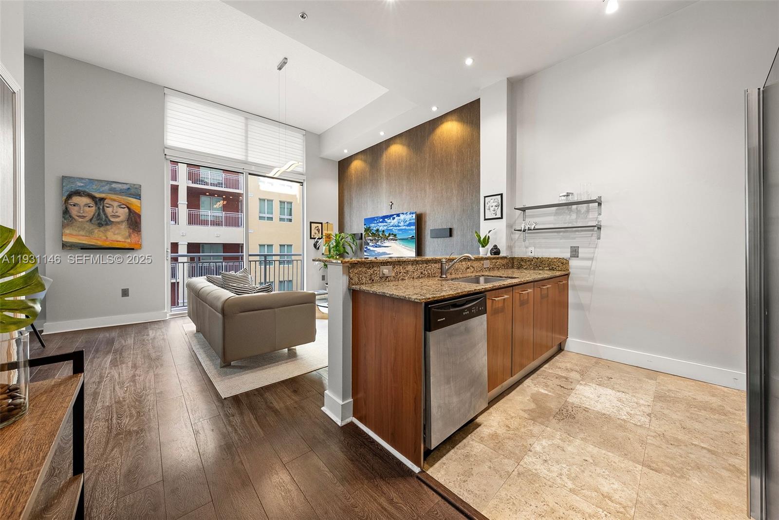 A kitchen with granite countertops and stainless steel appliances overlooks a living area with balcony — 9066 SW 73rd Ct # 405, Miami FL 33156, MIAMI, FL