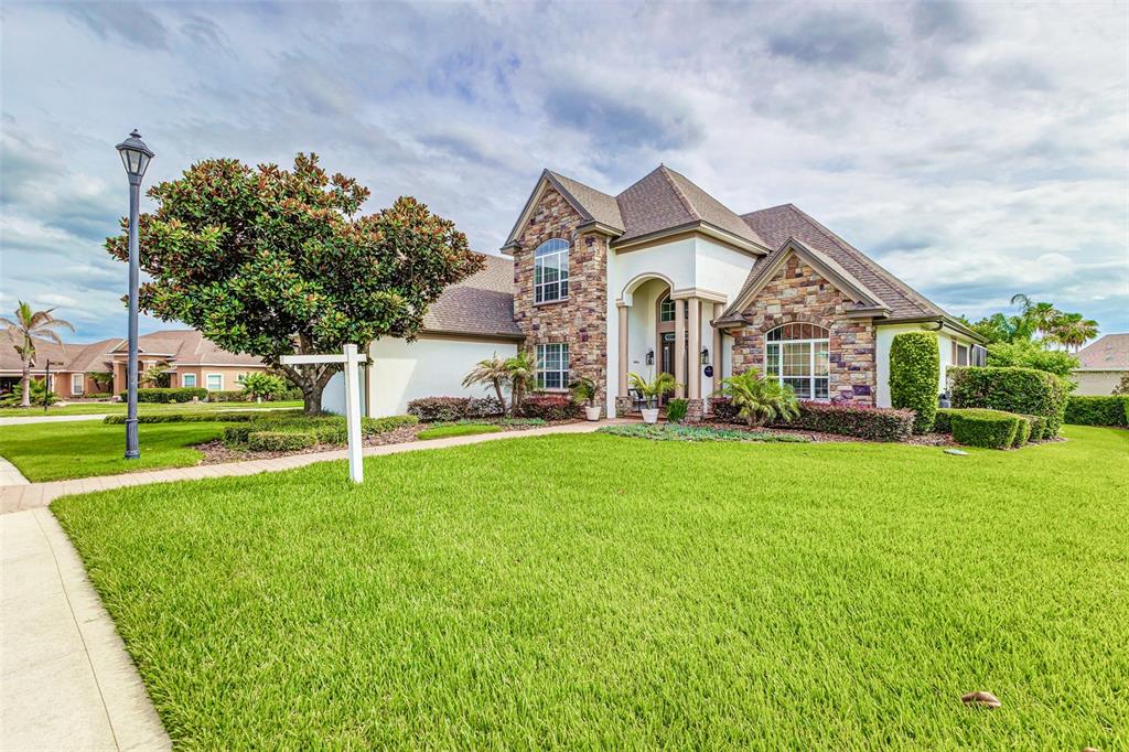 An outdoor pool and spa area with a covered patio and built-in kitchen — 7535 REFLECTIONS LAKE DRIVE, LAKELAND, FL