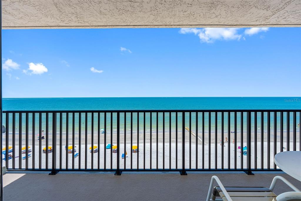 A balcony with a black metal railing overlooks a sandy beach and the ocean — 14300 GULF BOULEVARD UNIT 501, MADEIRA BEACH, FL