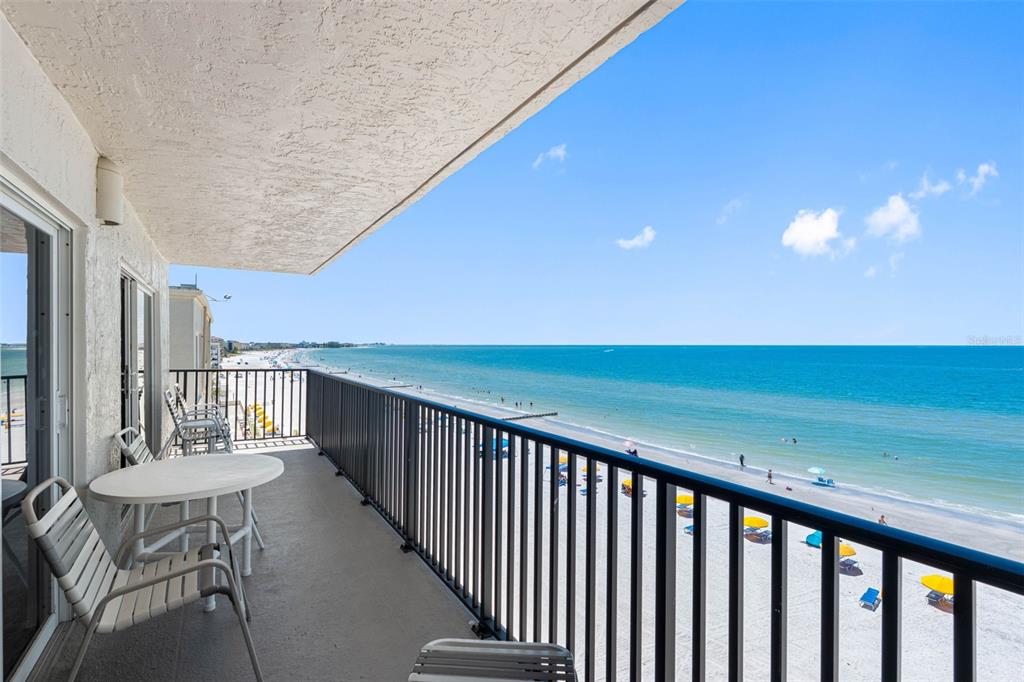 A balcony with a table and chairs overlooks a sandy beach and the ocean — 14300 GULF BOULEVARD UNIT 501, MADEIRA BEACH, FL