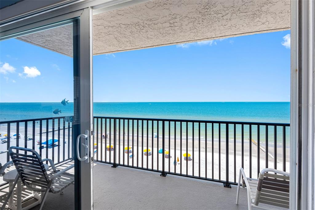 A balcony with a black metal railing overlooks a sandy beach and the ocean — 14300 GULF BOULEVARD UNIT 501, MADEIRA BEACH, FL