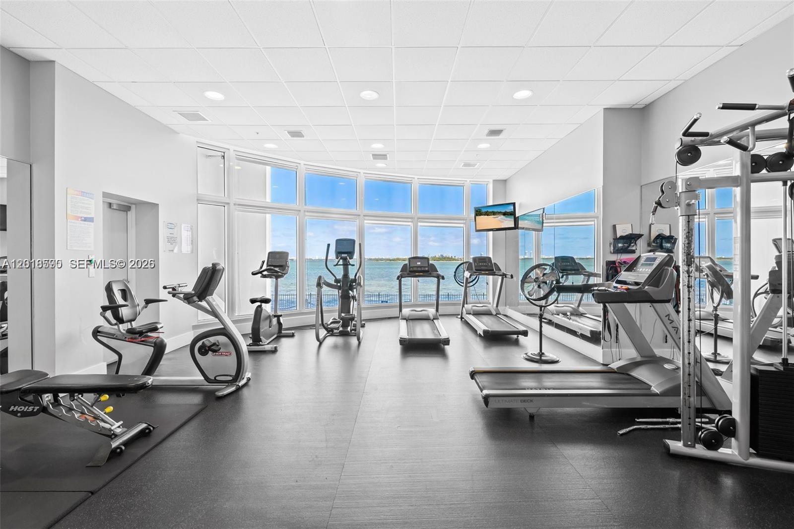 A fitness center features various exercise machines and large windows overlooking the ocean — 725 NE 22nd St, Miami FL 33137, MIAMI, FL