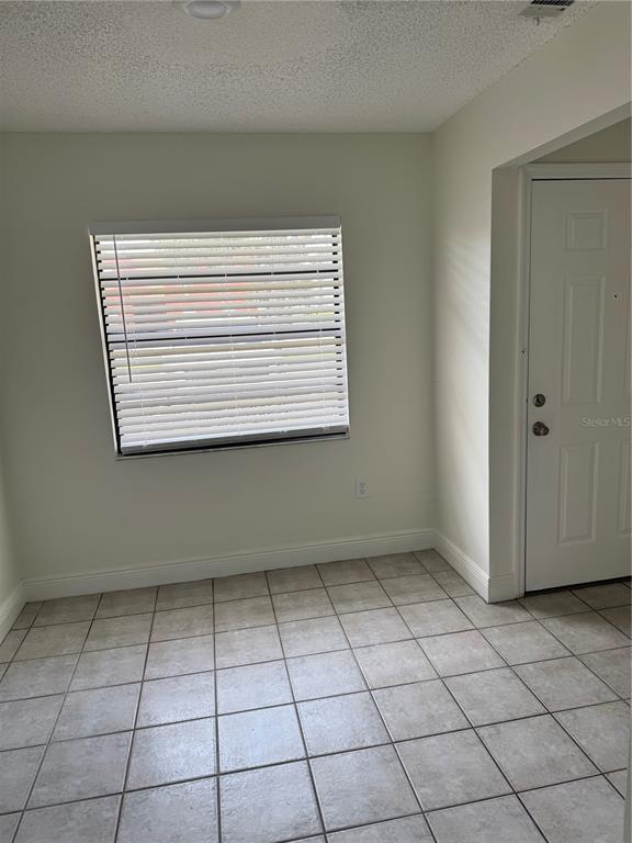 A room with light-colored walls, tiled flooring, a window with blinds, and a white door — 2219 CARIBBEAN DRIVE S UNIT 27, KISSIMMEE, FL