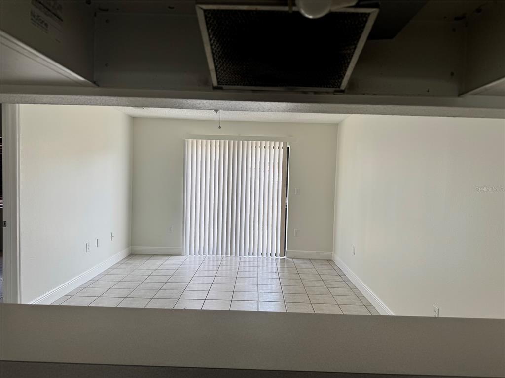 A view from a kitchen counter looking into a living room with tiled floors — 2219 CARIBBEAN DRIVE S UNIT 27, KISSIMMEE, FL