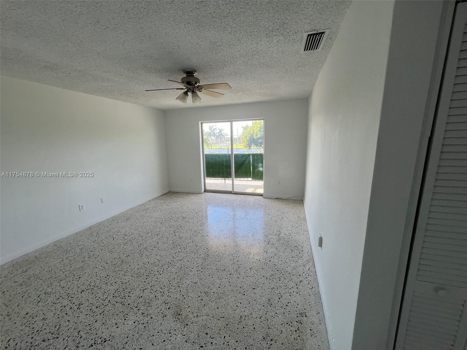 An empty room features white walls, a popcorn ceiling, a ceiling fan, and terrazzo flooring — 887 W 29th St # 2, Hialeah FL 33012, HIALEAH, FL
