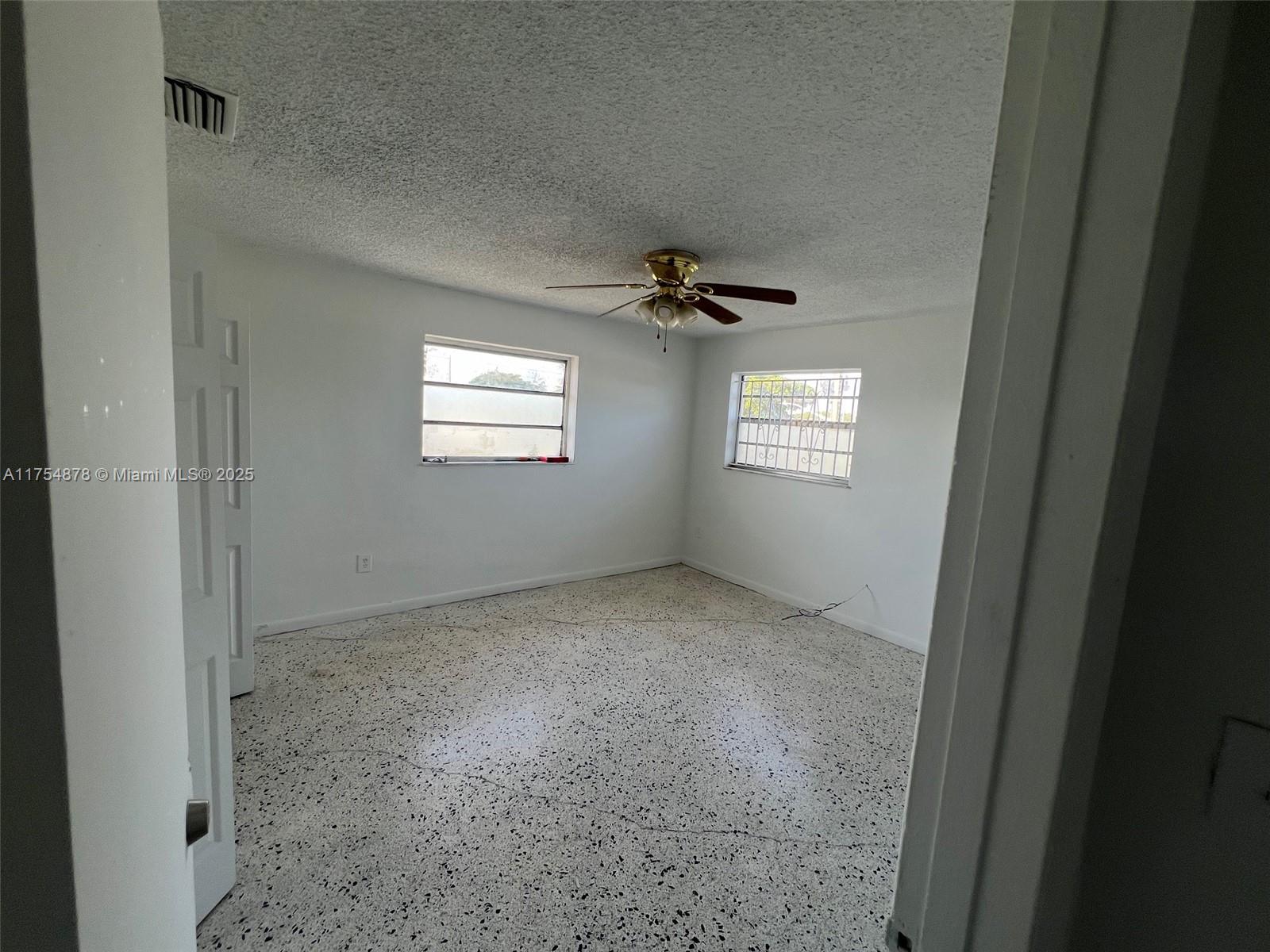 An empty bedroom features white walls, a ceiling fan, and speckled terrazzo flooring — 887 W 29th St # 2, Hialeah FL 33012, HIALEAH, FL