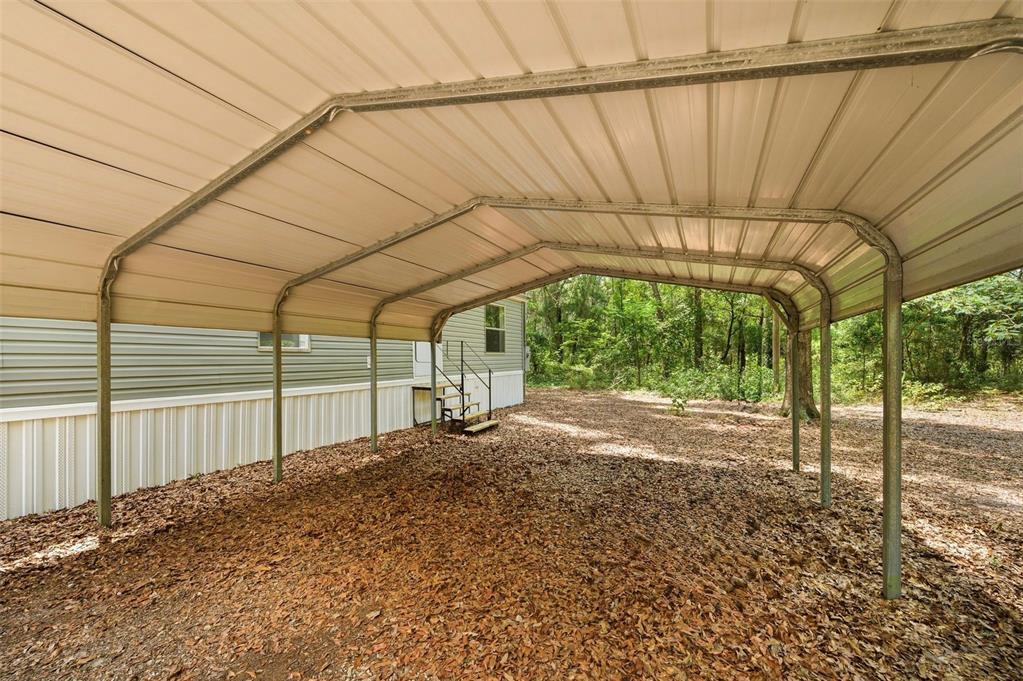 A metal carport stands next to a mobile home on a lot covered in leaves — 25697 21ST ROAD, O'BRIEN, FL