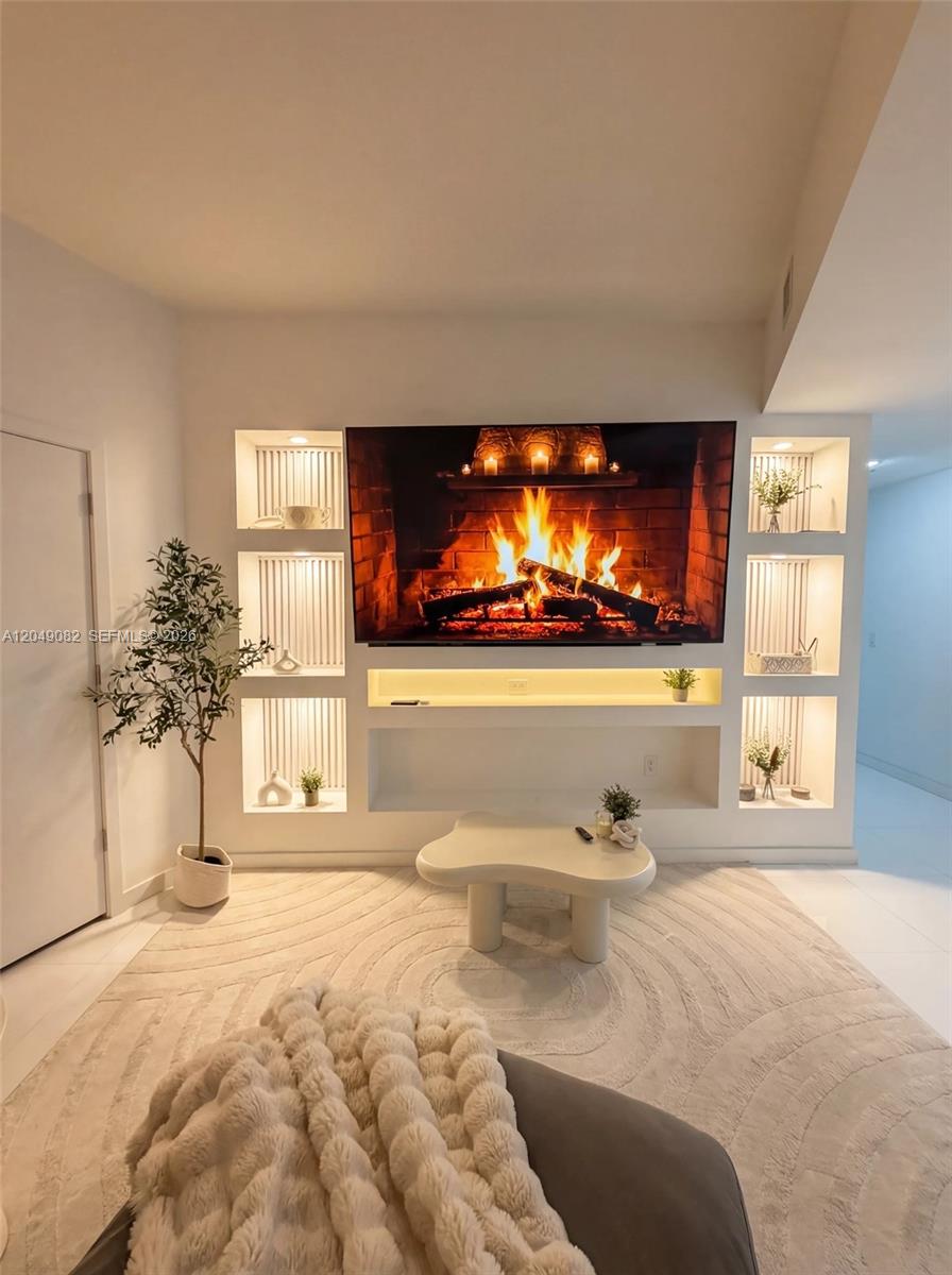 A living room features a wall-mounted television above built-in shelving with integrated lighting — 851 NE 1st Ave # 2301, Miami FL 33132, MIAMI, FL