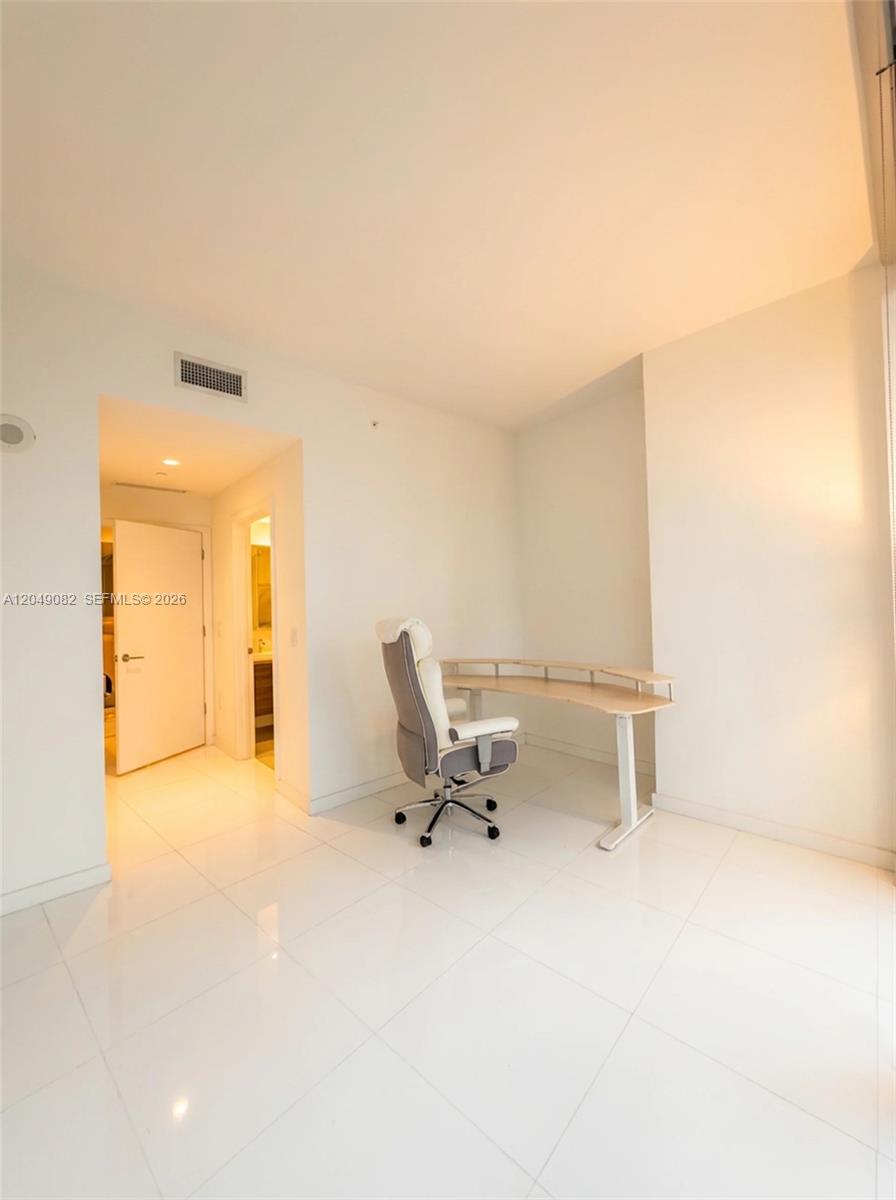 A minimalist home office features a curved desk, an ergonomic chair, and white tile flooring — 851 NE 1st Ave # 2301, Miami FL 33132, MIAMI, FL