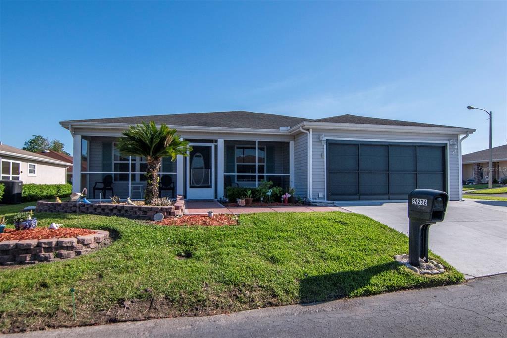 A single-story house with a screened-in front porch, a two-car garage, and a landscaped yard — 29236 KAPALUA WAY, SAN ANTONIO, FL