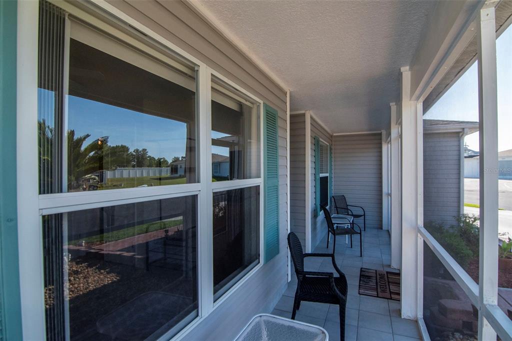 A screened-in porch features light-colored tile flooring, gray siding, and several black outdoor chairs — 29236 KAPALUA WAY, SAN ANTONIO, FL