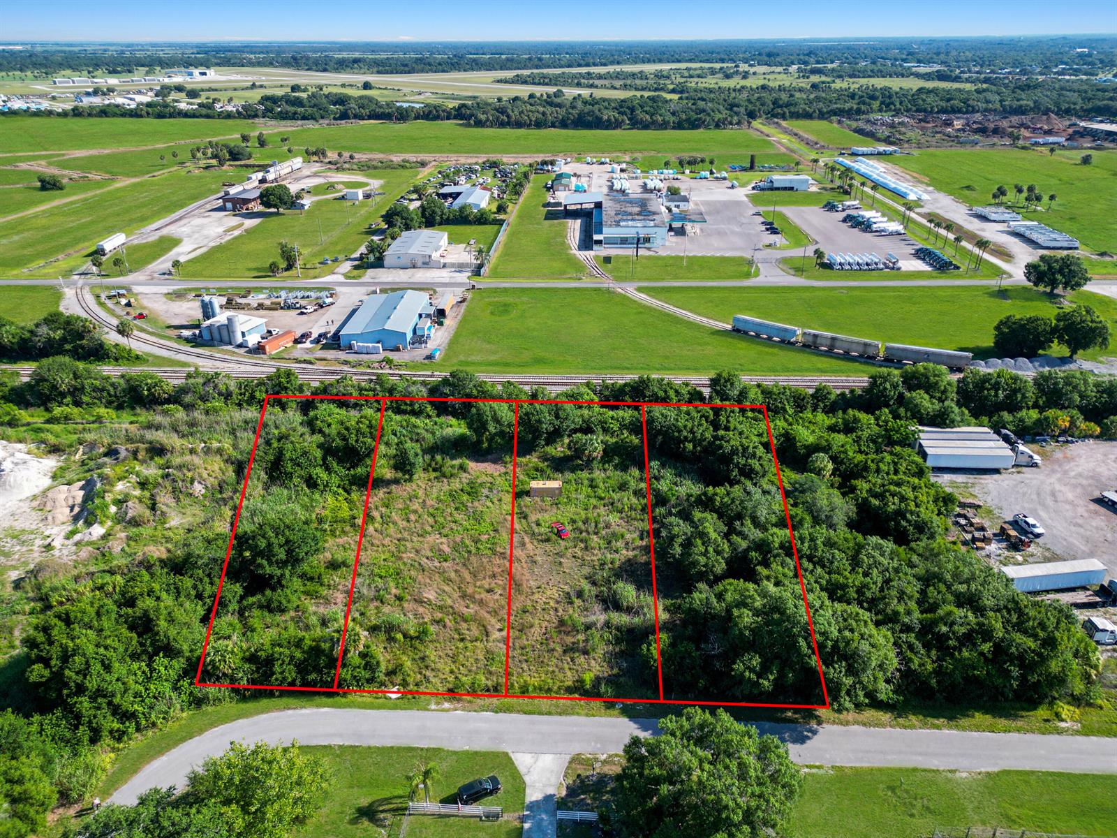 An aerial view shows four adjacent vacant lots outlined in red near a railroad track — . NW 7th Court, Okeechobee FL 34972, OKEECHOBEE, FL