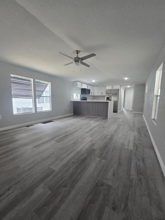 An open-concept living area features gray wood-look flooring, a ceiling fan, and a kitchen island — 1807 PAULINE DRIVE UNIT 279, LAKE ALFRED, FL