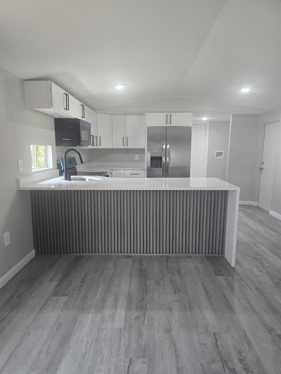 A kitchen features white cabinets, stainless steel appliances, and a gray slatted breakfast bar — 1807 PAULINE DRIVE UNIT 279, LAKE ALFRED, FL