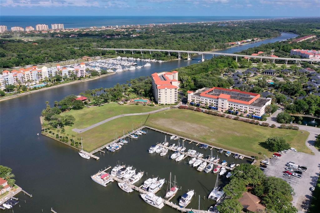 An aerial view shows a marina with docked boats, a large grassy lot, and buildings — 146 PALM COAST RESORT BOULEVARD UNIT 107, PALM COAST, FL