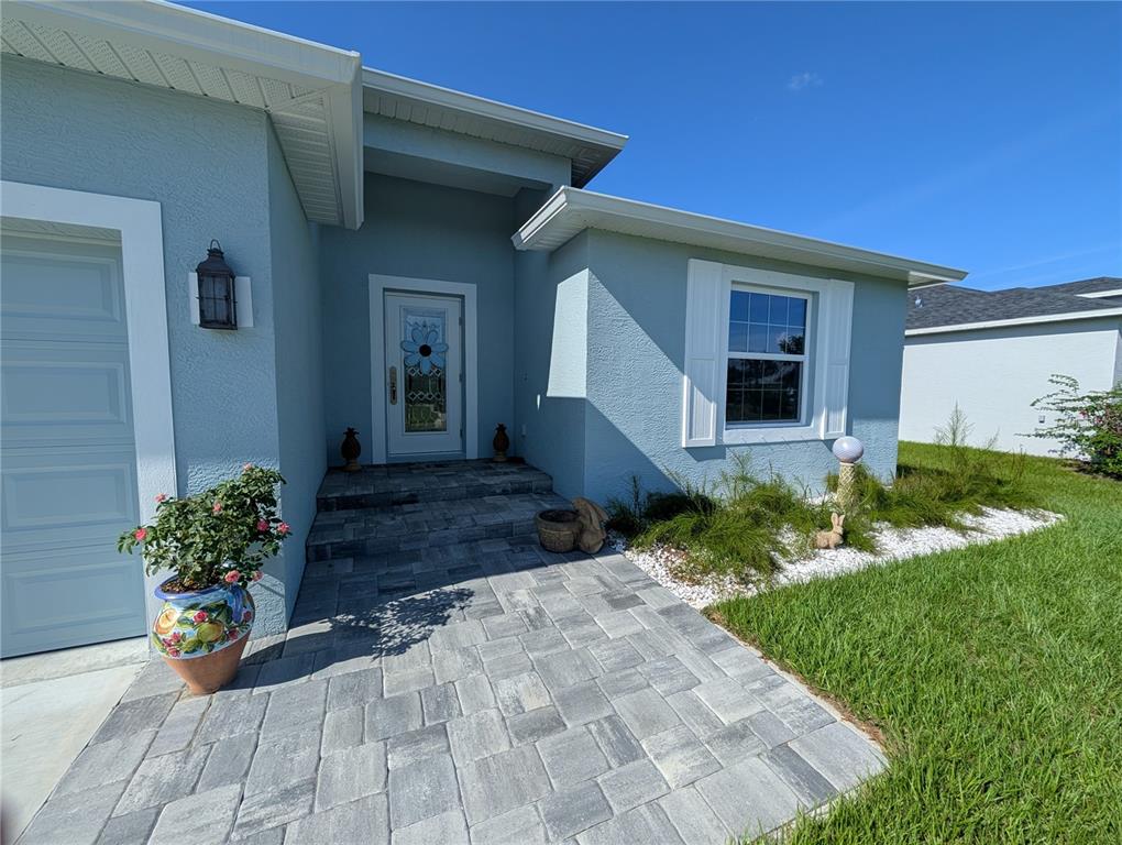 The exterior of a light blue house features a paver walkway and a front door — 12190 KNEELAND TERRACE, PORT CHARLOTTE, FL