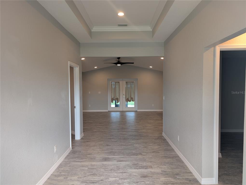 A hallway with gray wood-look flooring leads to a living area with French doors — 12190 KNEELAND TERRACE, PORT CHARLOTTE, FL
